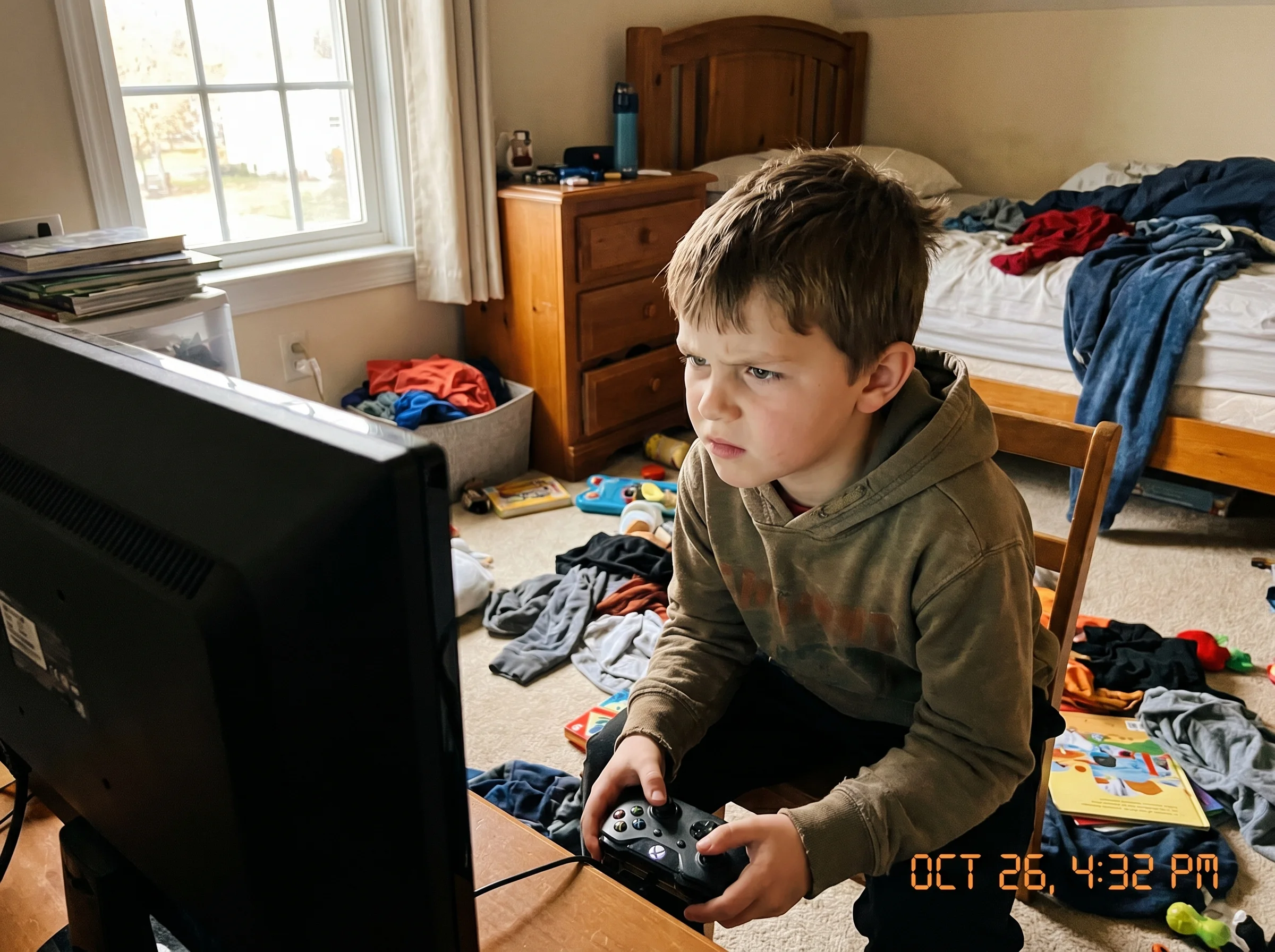 A young boy mid-game with an intense focused expression, brow furrowed, leaning toward a computer monitor in a messy bedroom