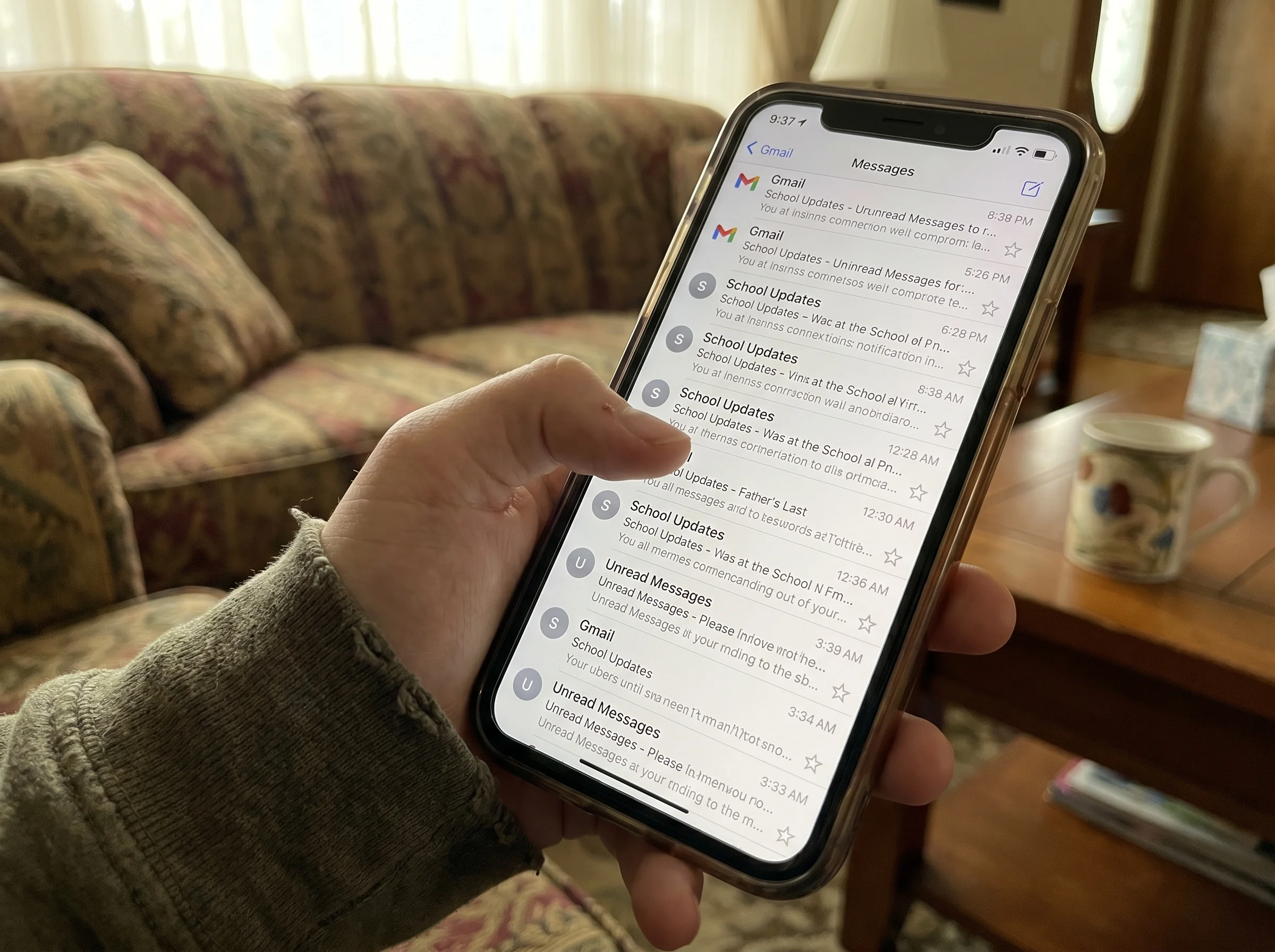Close-up of a smartphone screen showing a flood of email notifications stacking up, held in a teenager's hand