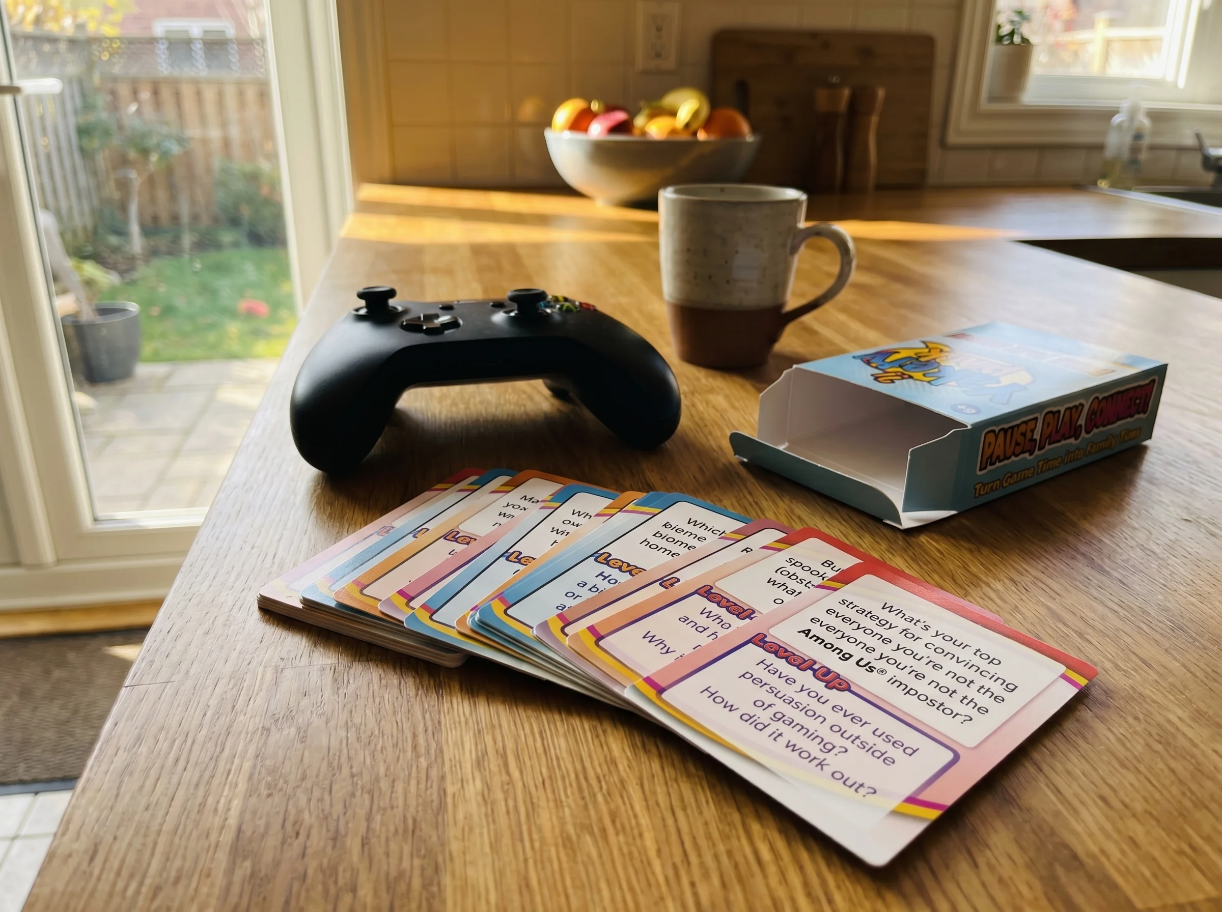 A stack of colorful conversation cards fanned out next to a gaming controller on a kitchen counter, natural morning light