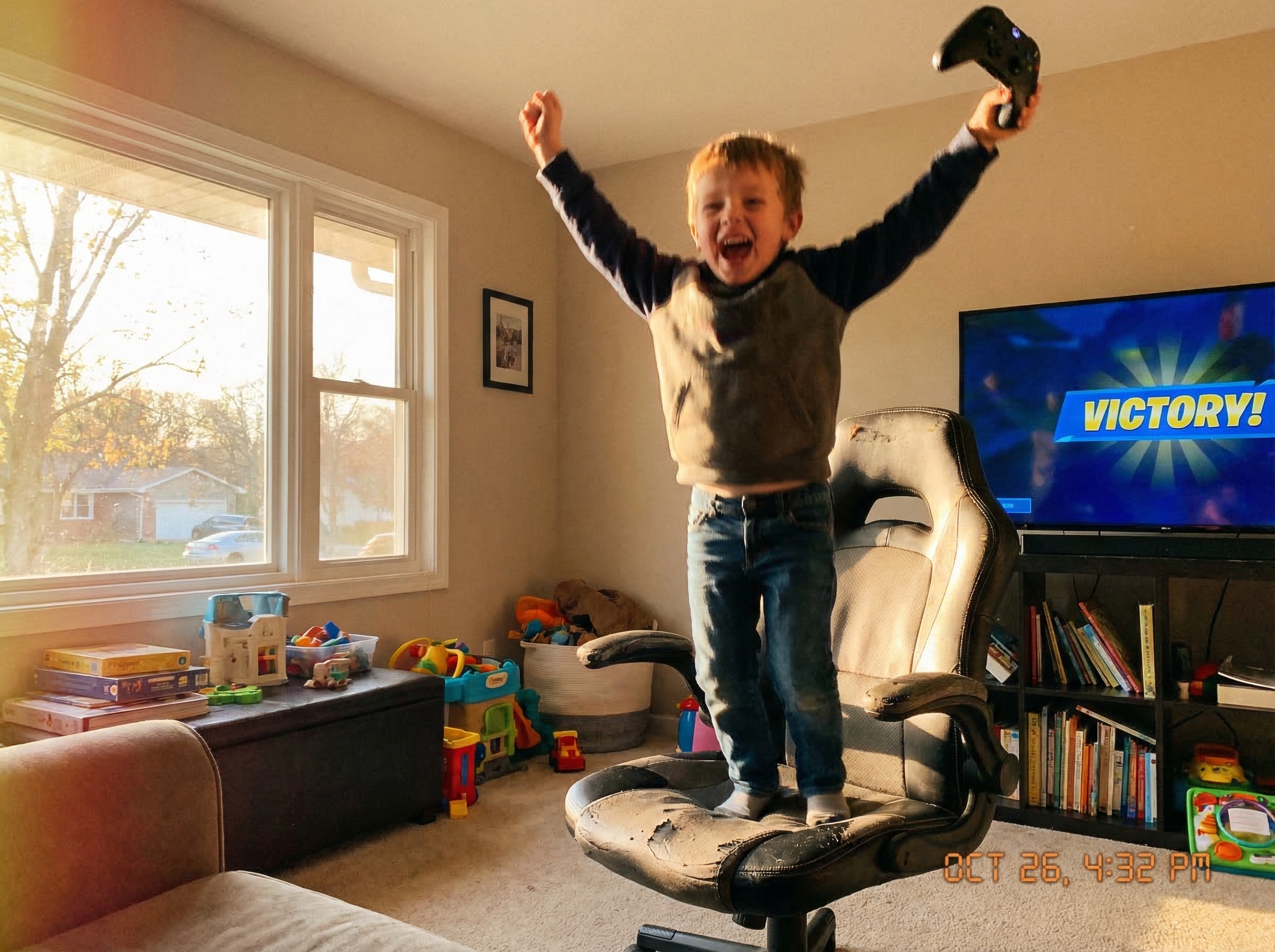 Kid jumping up from gaming chair with arms raised in victory, controller still in hand, pure joy on face with afternoon sunli