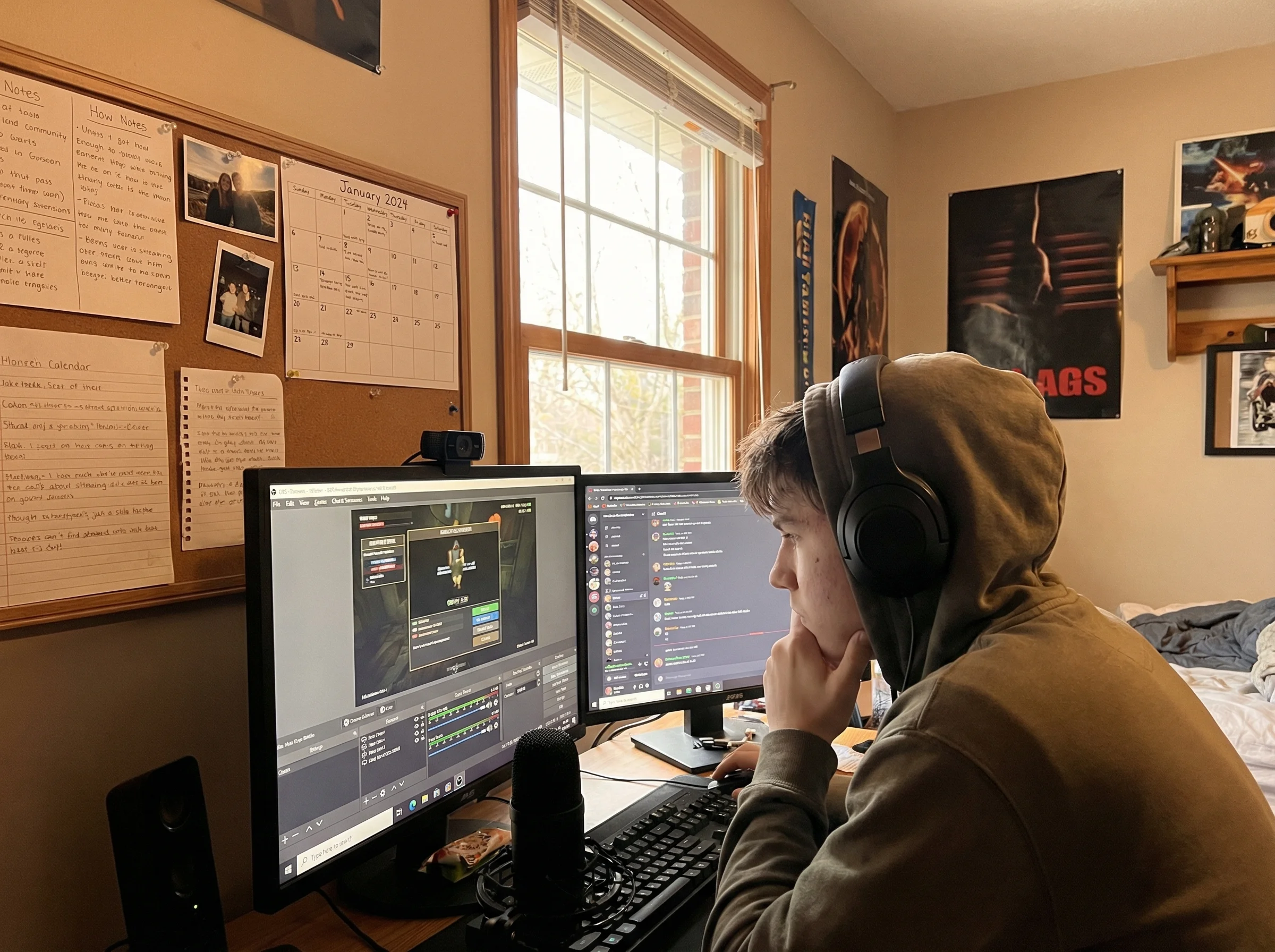 A teenager at a dual-monitor gaming setup with streaming software visible on one screen, notes and schedules pinned to a boar