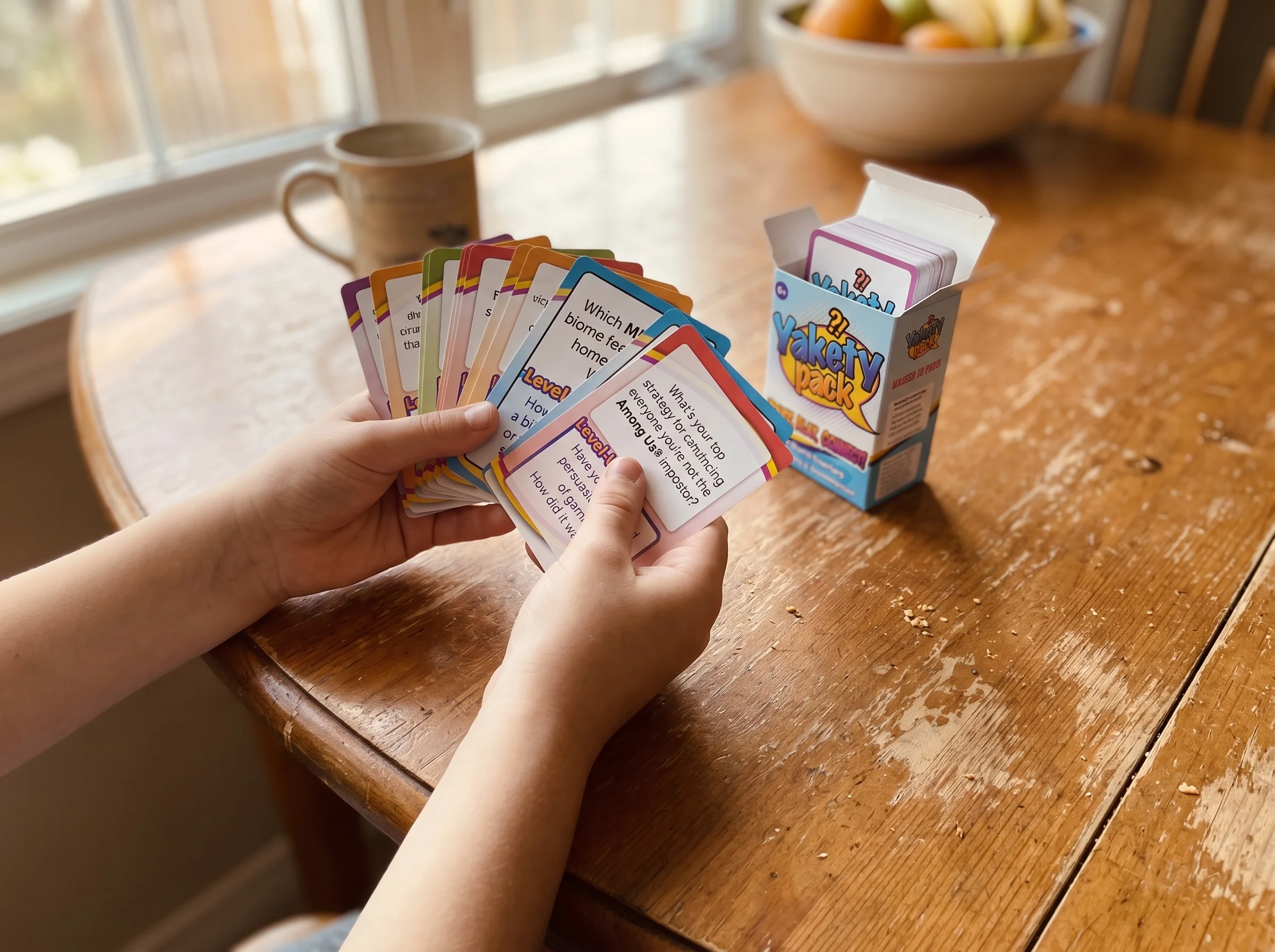 A kid's hands holding a fan of Pokemon trading cards spread out on a wooden kitchen table, soft natural light