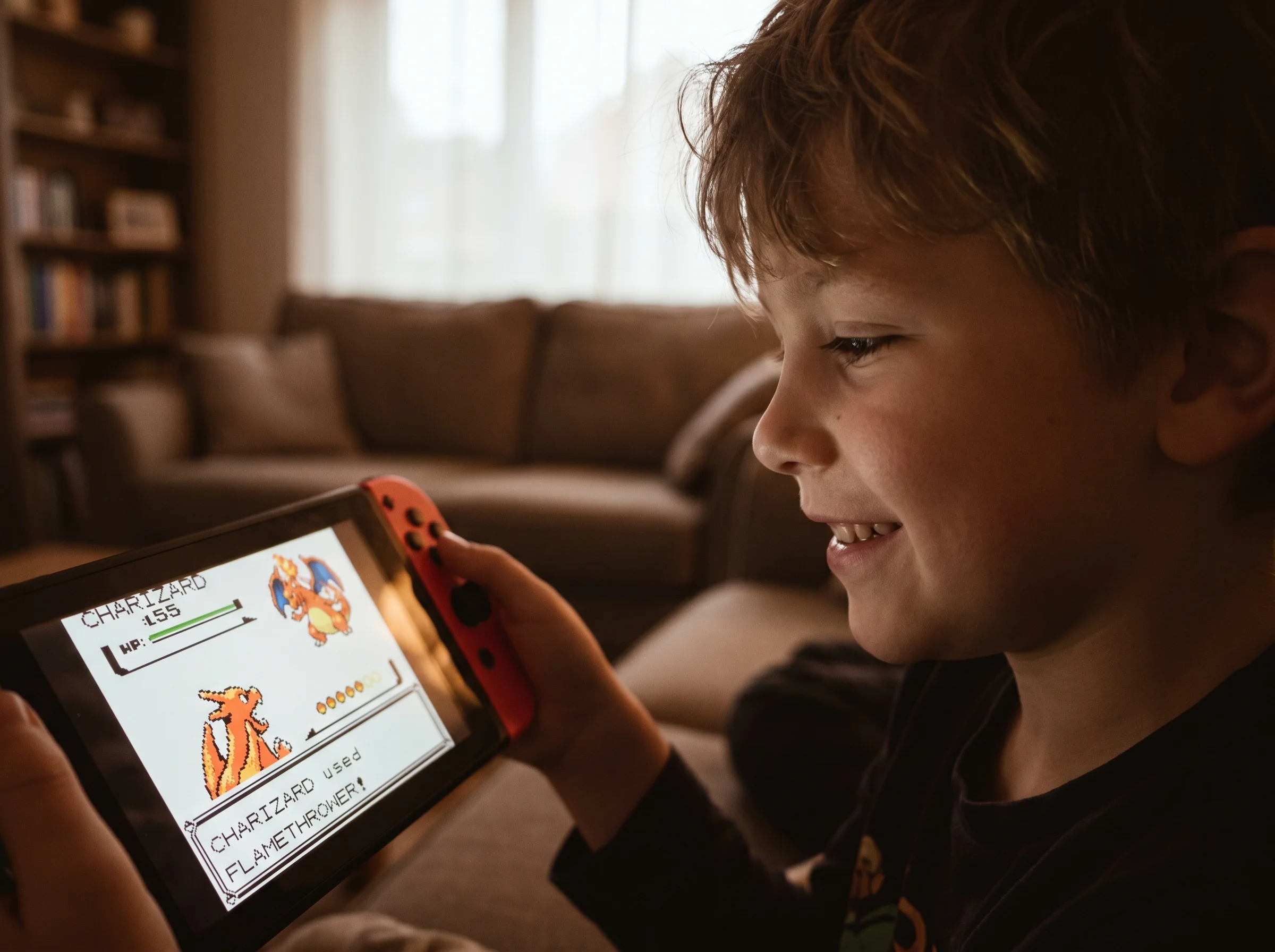 A handheld Nintendo Switch screen showing a Pokemon battle, blurred in the foreground with a kid's face lit up by the screen 