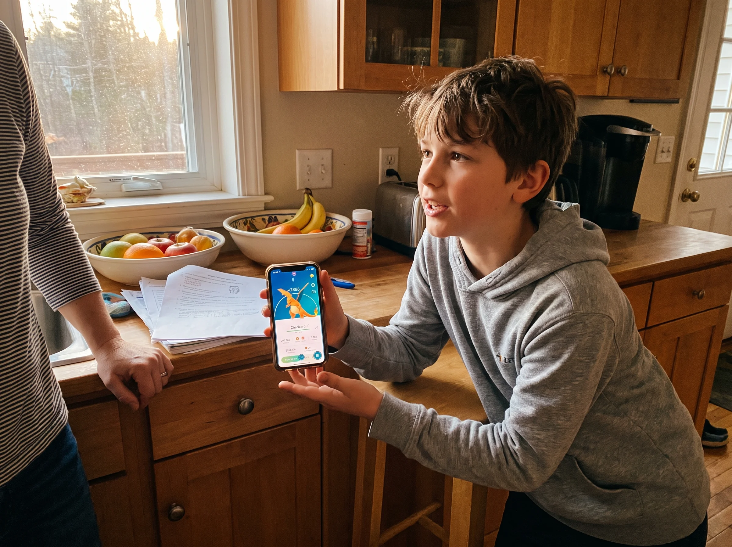 A pre-teen kid leaning against a kitchen counter holding a phone with a Pokemon app open, mid-sentence talking to a parent of