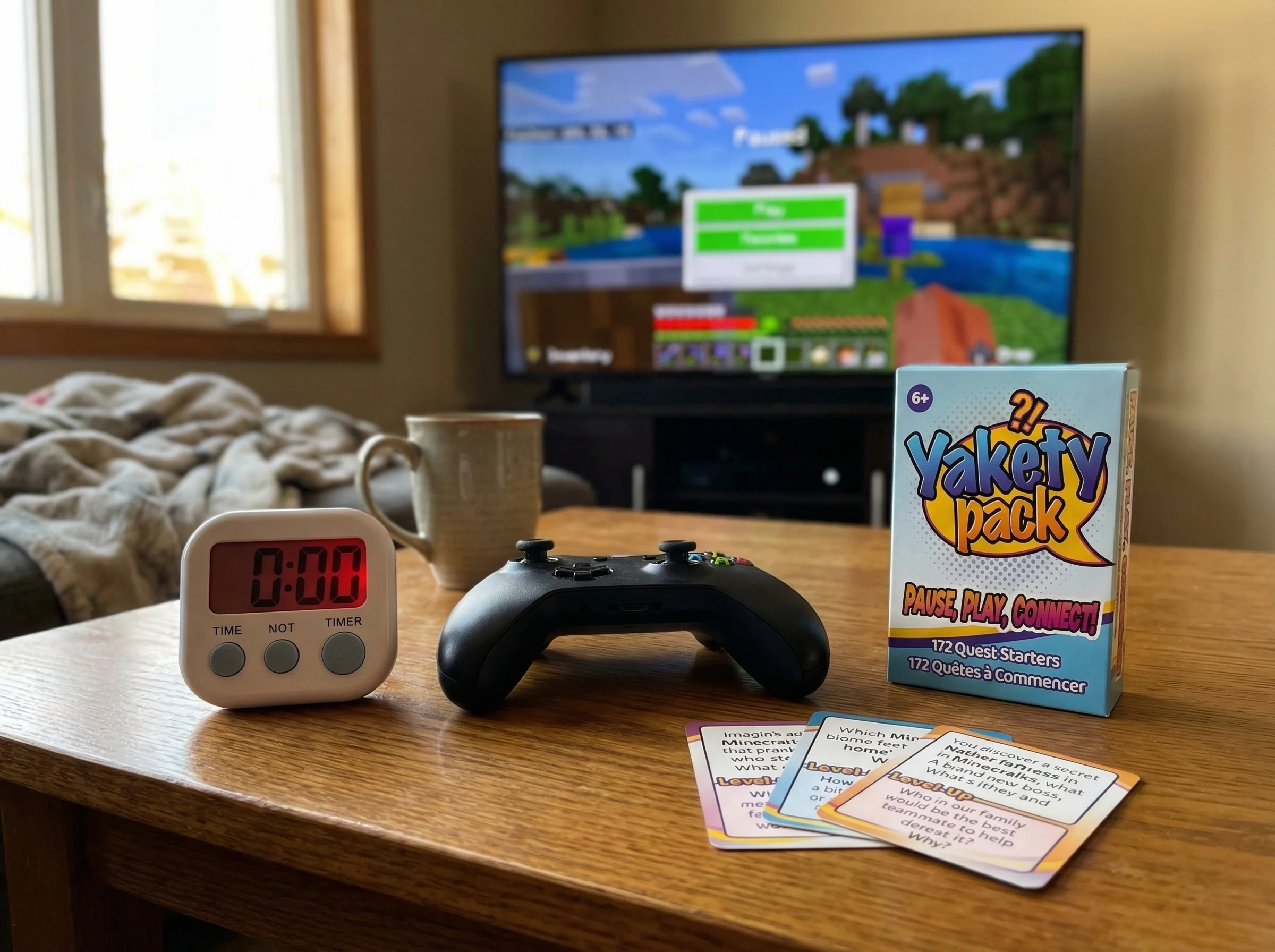 Close-up of a kitchen timer sitting next to a gaming controller, both on a coffee table with a paused game visible on the TV