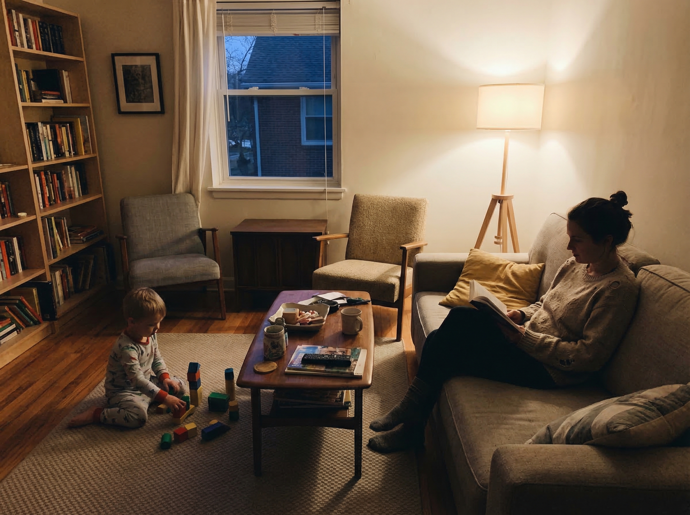 Evening scene with parent sitting nearby as child plays, both in comfortable silence, soft lamp light creating cozy atmospher