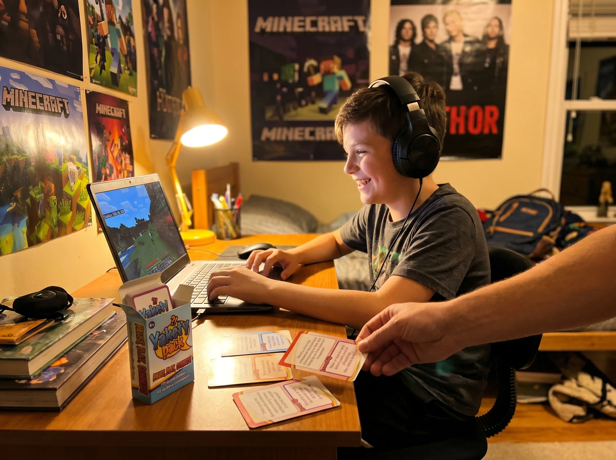 A 12-year-old sitting at a desk in their bedroom playing Minecraft on a laptop, headphones on, smiling at the screen, posters