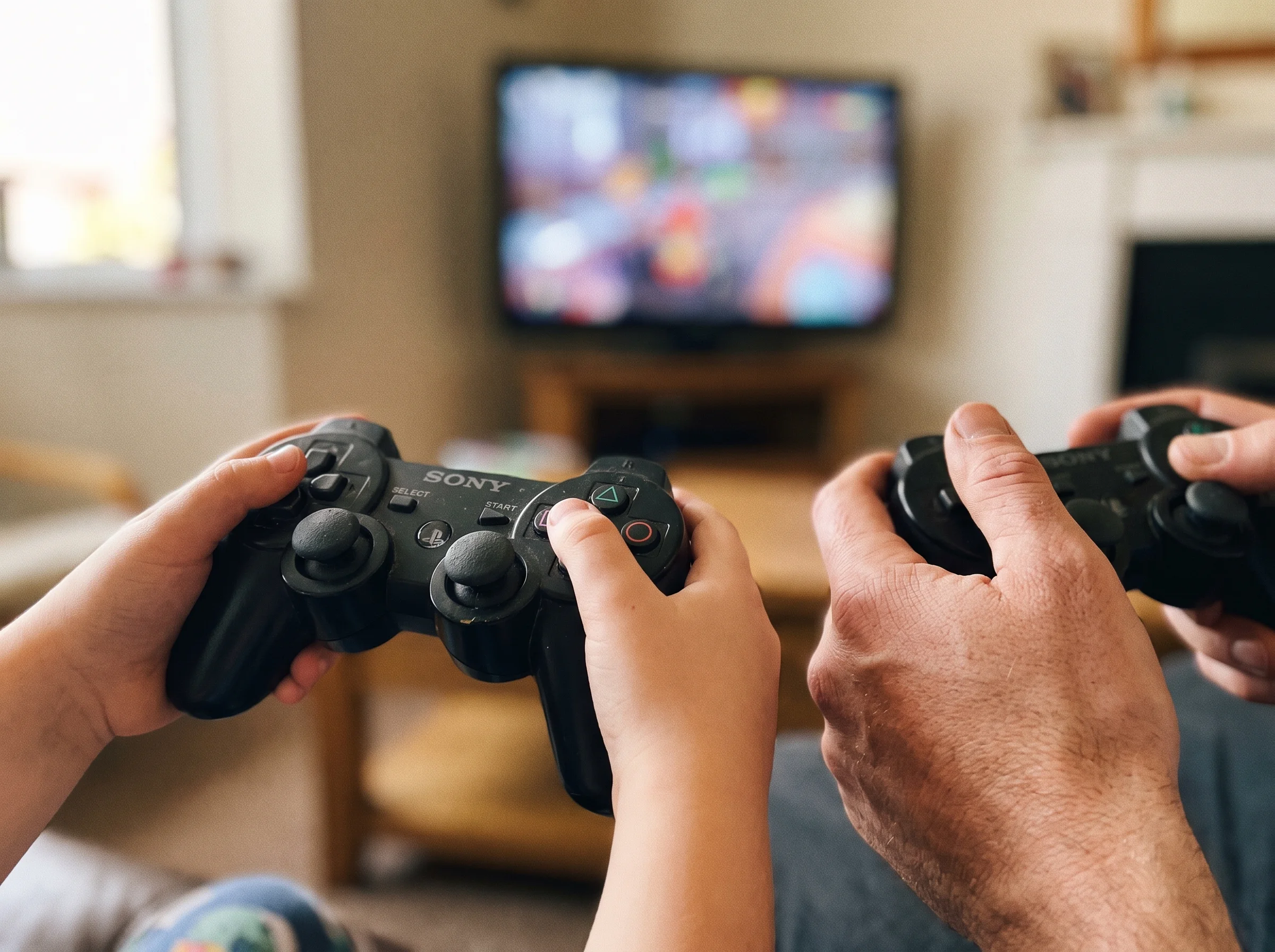 A close-up of a kid's hands holding a game controller with intense focus, dad's slightly older hands holding a second control