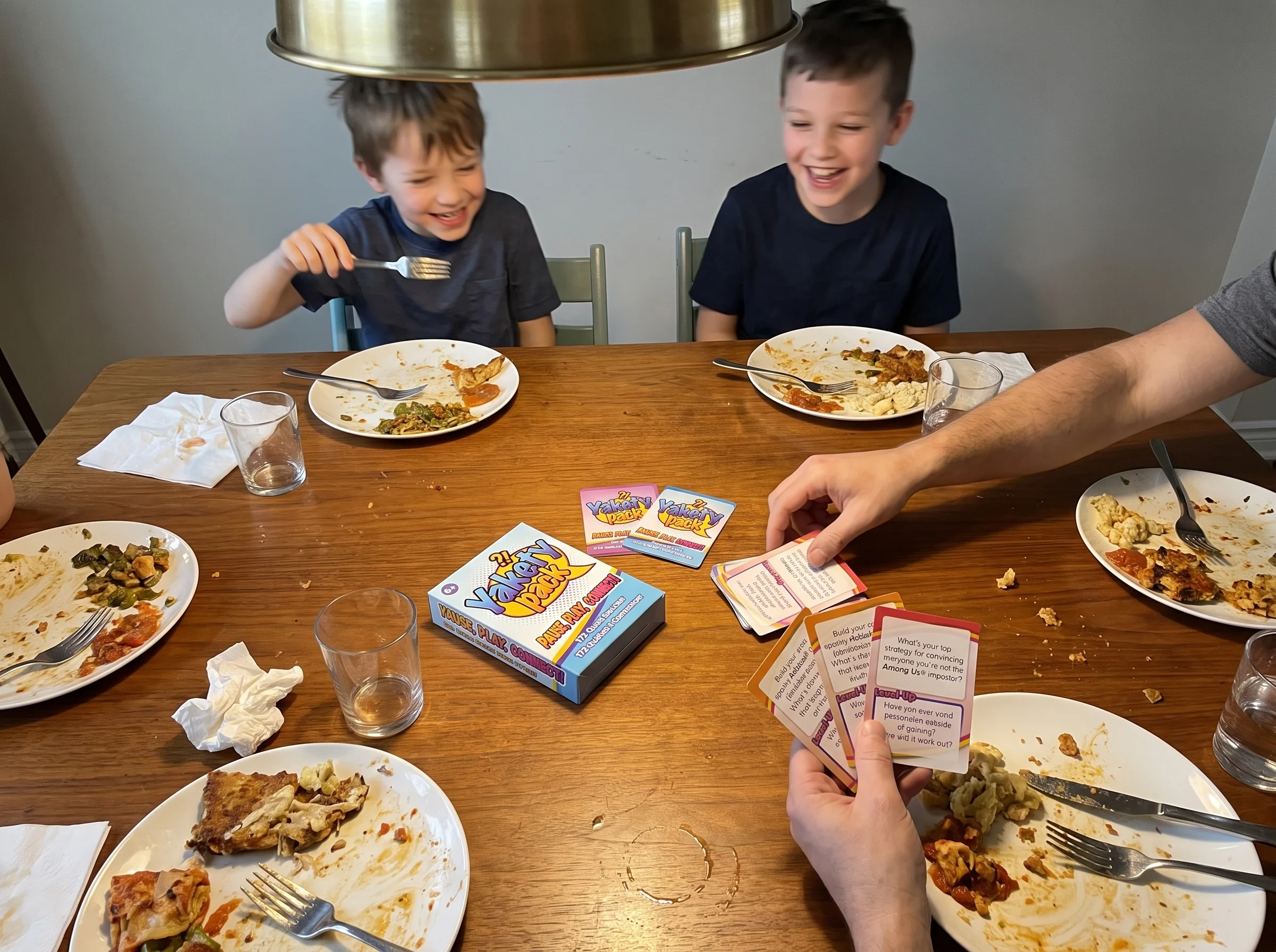 A family dinner table shot from above, plates half-eaten, a stack of conversation cards in the middle, kids laughing mid-sent