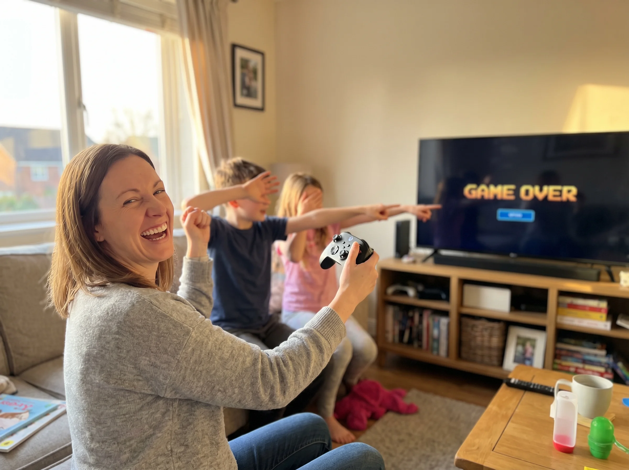 A mom triumphantly holding a game controller while kids in the background react dramatically to something happening on screen
