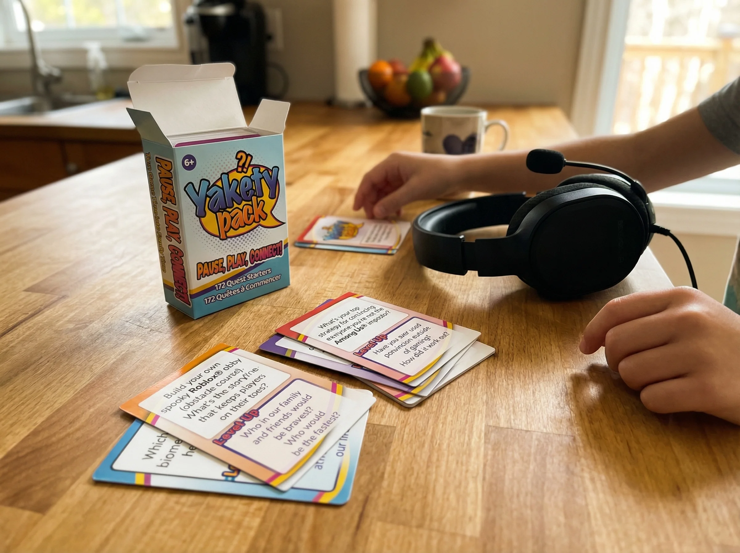 A kitchen counter scene with Yakety Pack conversation cards spread out next to a gaming headset, showing the blend of family
