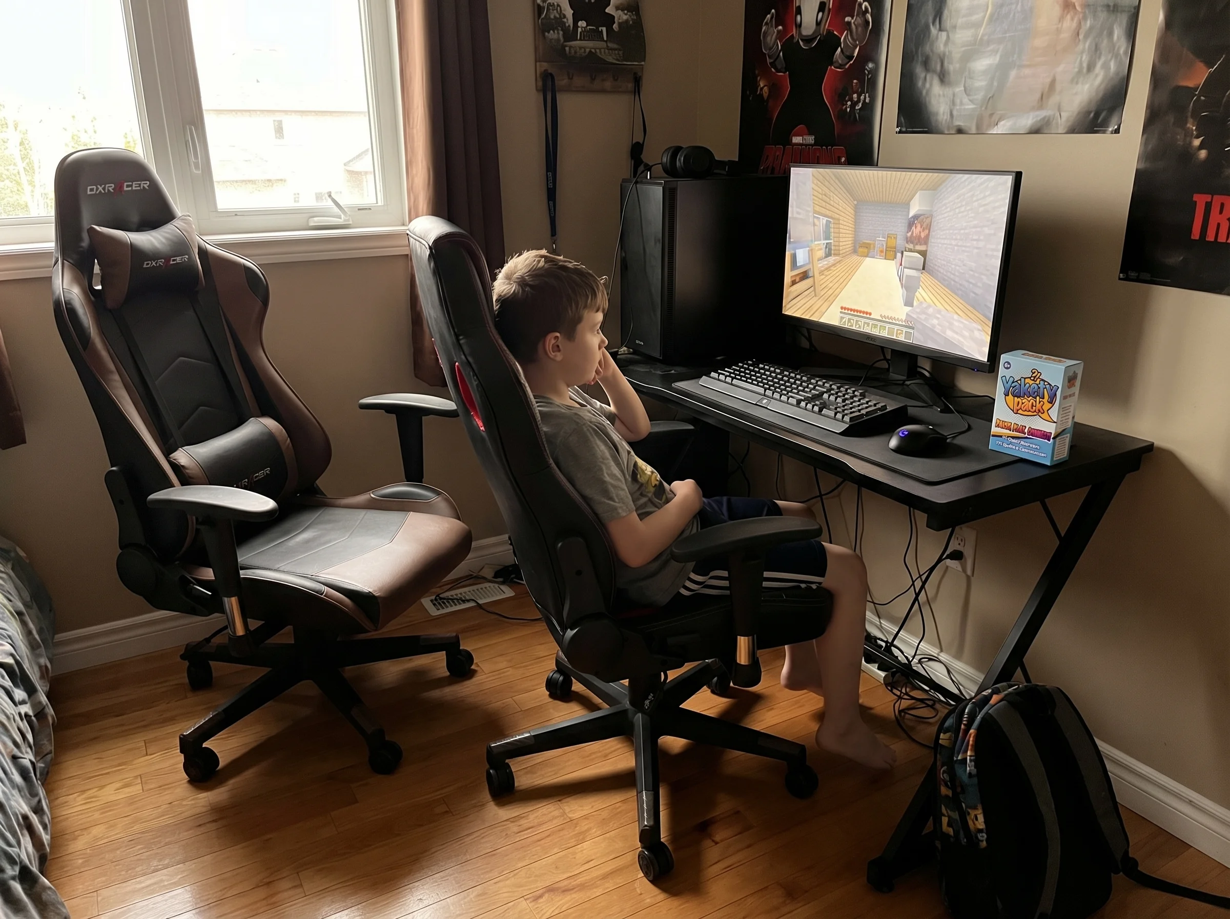 A young boy sitting alone at his gaming setup in a dimly lit room, empty gaming chairs beside him where friends used to sit,