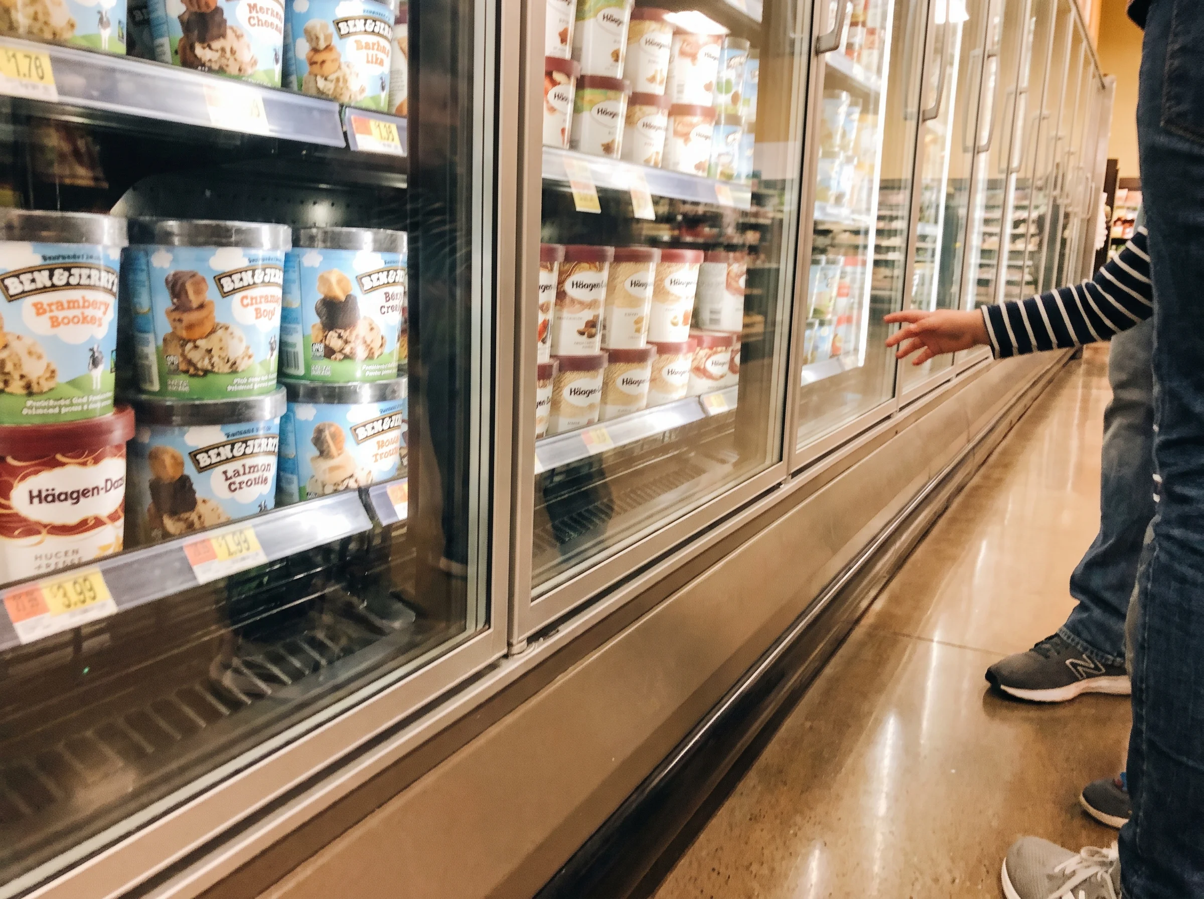 Grocery store freezer aisle from a kid's eye view, ice cream cartons visible, casual iPhone snap with slight motion blur