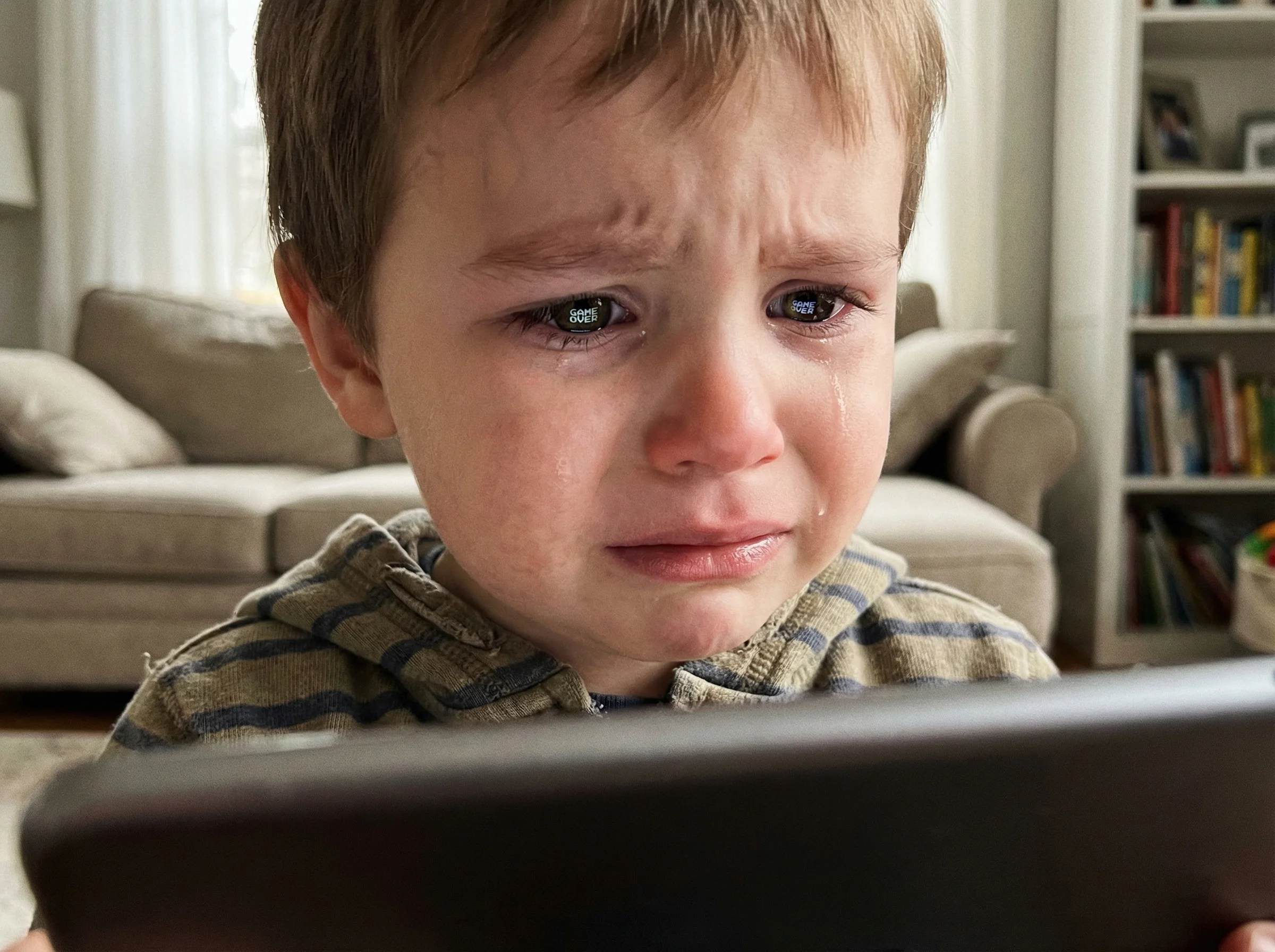 Close-up of a child's face showing genuine distress while looking at a game screen showing lost progress, tablet reflecting i