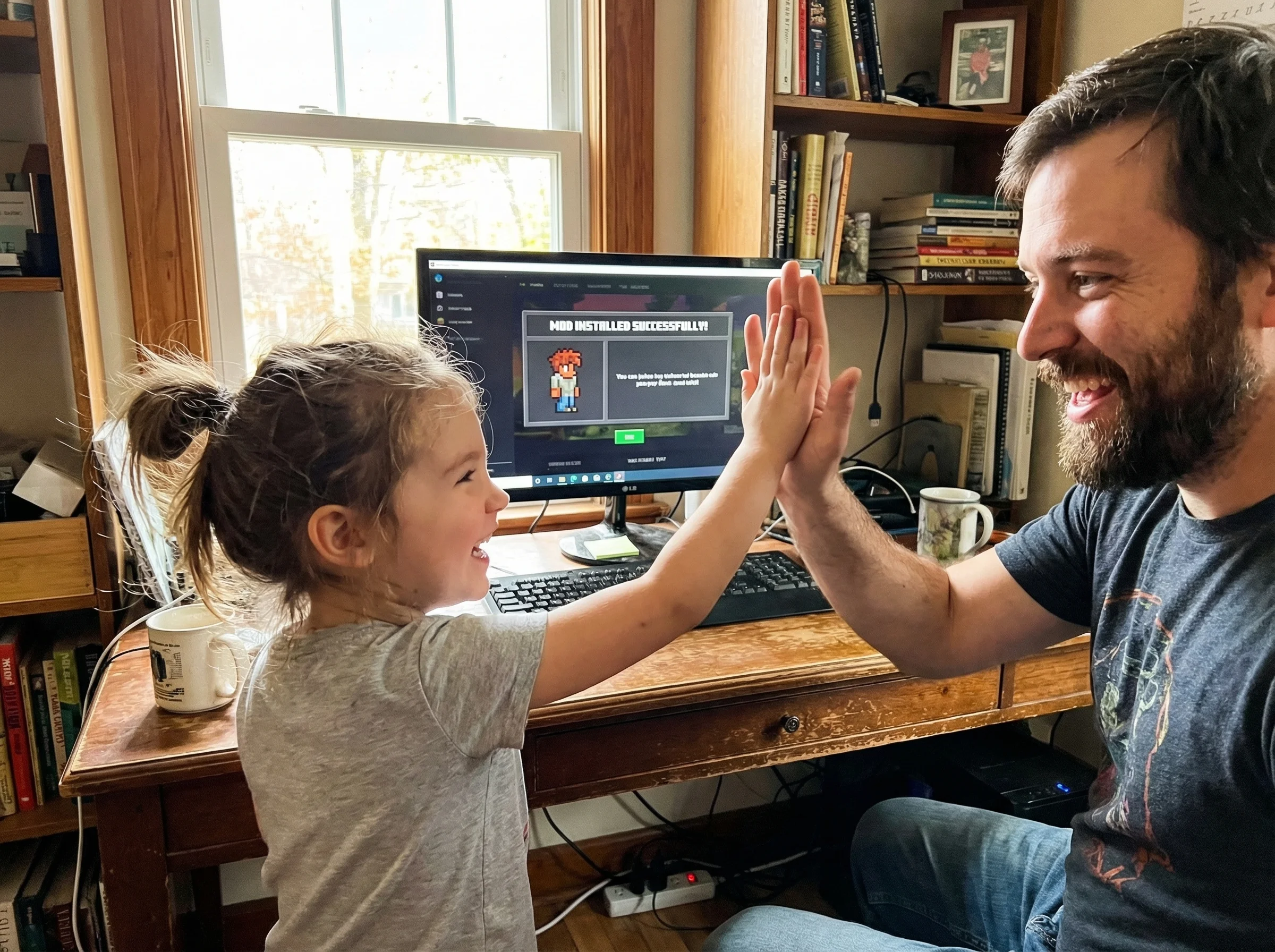 Parent and child high-fiving in front of computer screen showing successfully installed game mod, both faces lit up with genu